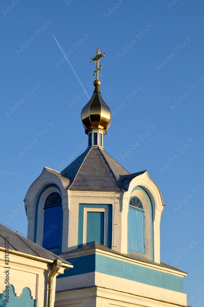 The gold dome of Christian church is against the background of the blue sky.The plane flies in the sky.