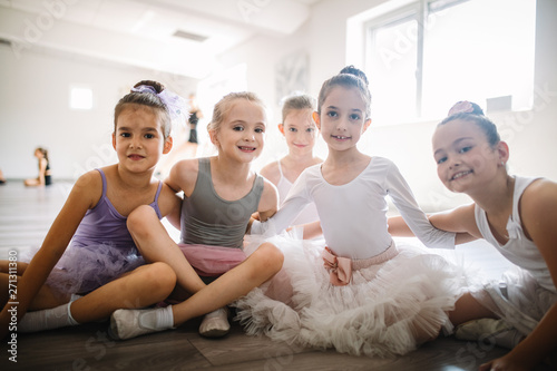 Group of fit happy children exercising ballet in studio together