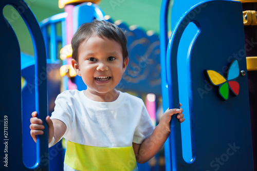Smiling young boy holding on from a kids playground jungle gym with an excited look and ready to have fun.