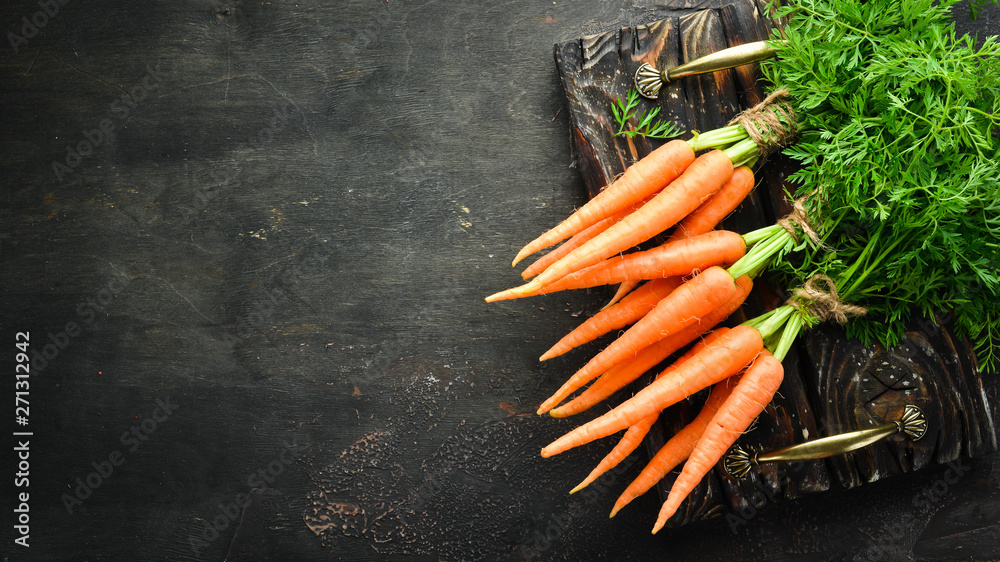 Fresh carrots on a black wooden background. Top view. - obrazy, fototapety, plakaty 