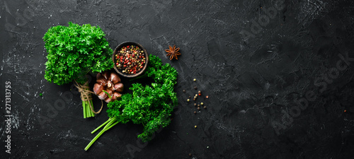 Parsley, spices and herbs. On a black stone background. Top view. Free space for your text.