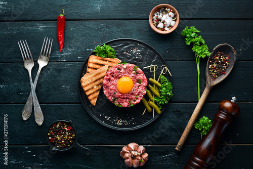 Bild auf Leinwand Beef steak tartare with raw egg yolk, pickled cucumber and onions