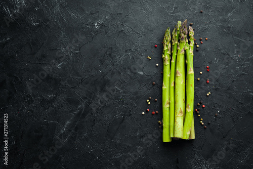Fresh green asparagus on a black stone background. Top view. Free space for your text.