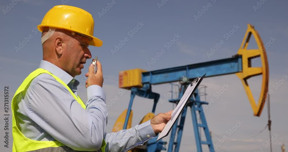 Engineer Working in Oil Extraction Industry Talk to a Handheld Transceiver Engineer Working in Oil Extraction Industry Talk to a Handheld Transceiver