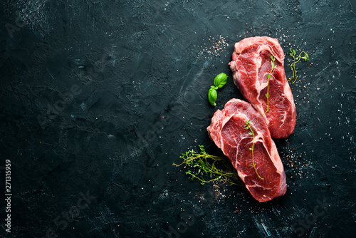 Raw Steak Ribeye. On a black stone table. Top view. Free space for your text.