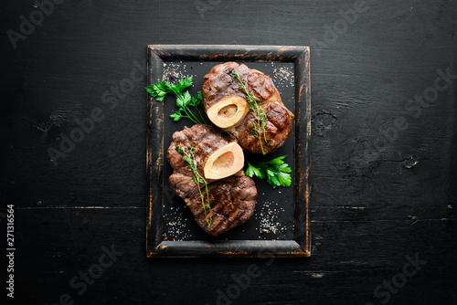 Beef shank roasted on a grill on a wooden background. Top view. Free space for your text.