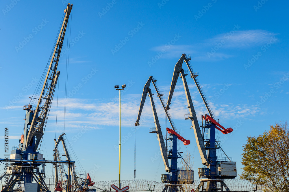 Large iron port crane while working on blue sky background.