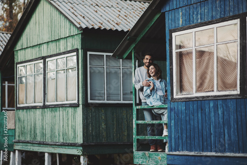 Smiling couple standing on porch of wooden cabin.