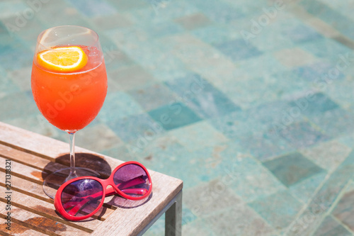 exotic cocktail and sunglasses by the pool of a luxury hotel
