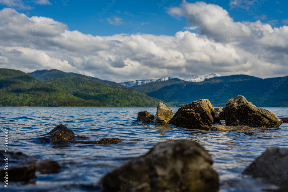 low angle view over water with many rocks in the foreground and mountains in background