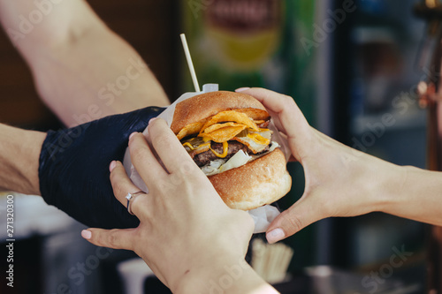 the cook gives a delicious packaged burger to the buyer. street food. close-up
