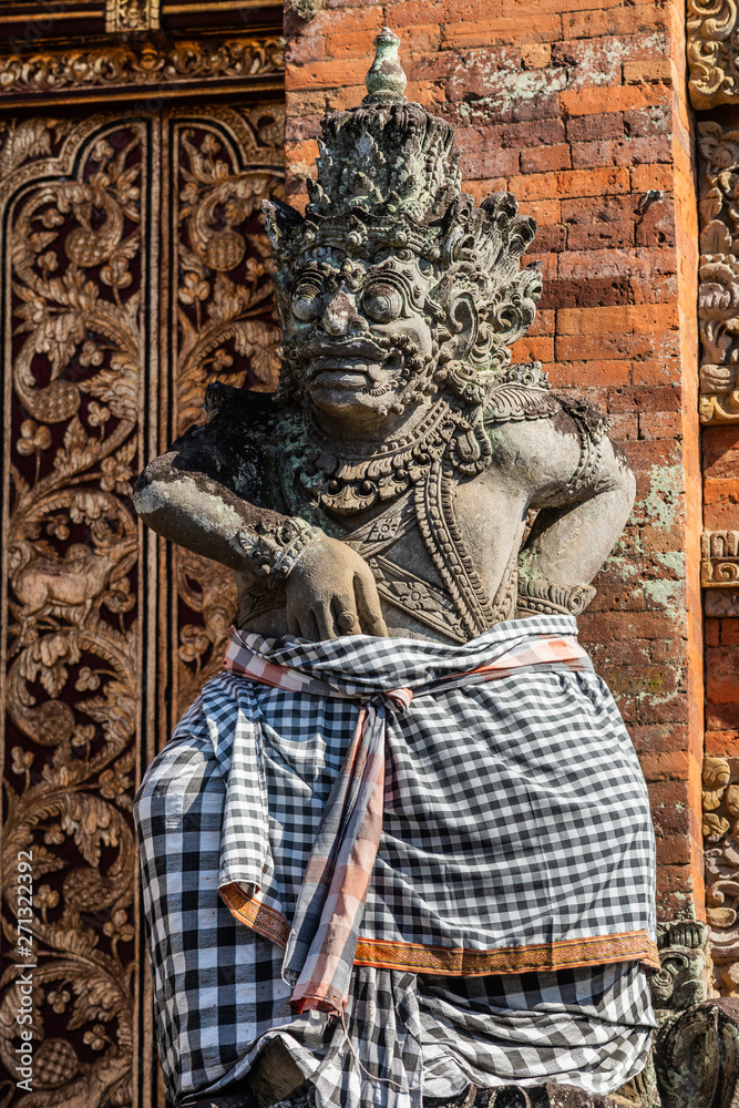 Ubud, Bali, Indonesia - February 26, 2019: Batuan Temple. Closeup of gray stone dwarapalaka, guard, right in front of door of Kori Agung, main shrine.