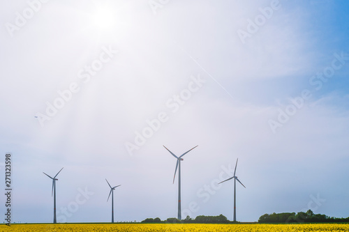 Germany, Juechen, wind wheel behind rape field at backlight photo