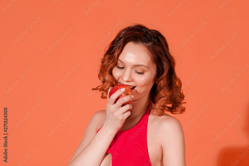 the girl biting the Apple on a red background the girl biting the Apple on a red background
