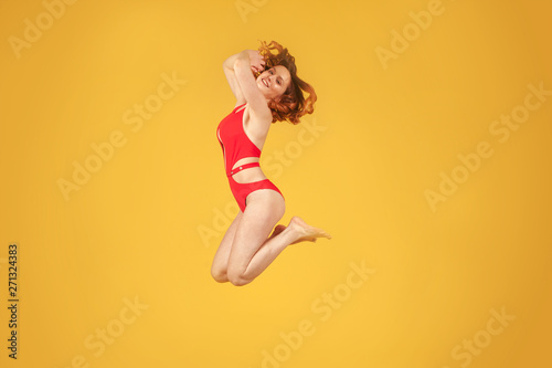 Fototapeta Naklejka Na Ścianę i Meble -  beautiful girl in jump on uniform yellow background