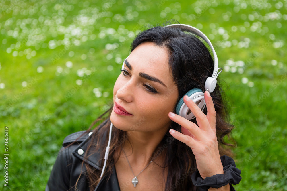 Portrait of young woman with white headphones, wearing black leather jacket Portrait of young woman with white headphones, wearing black leather jacket