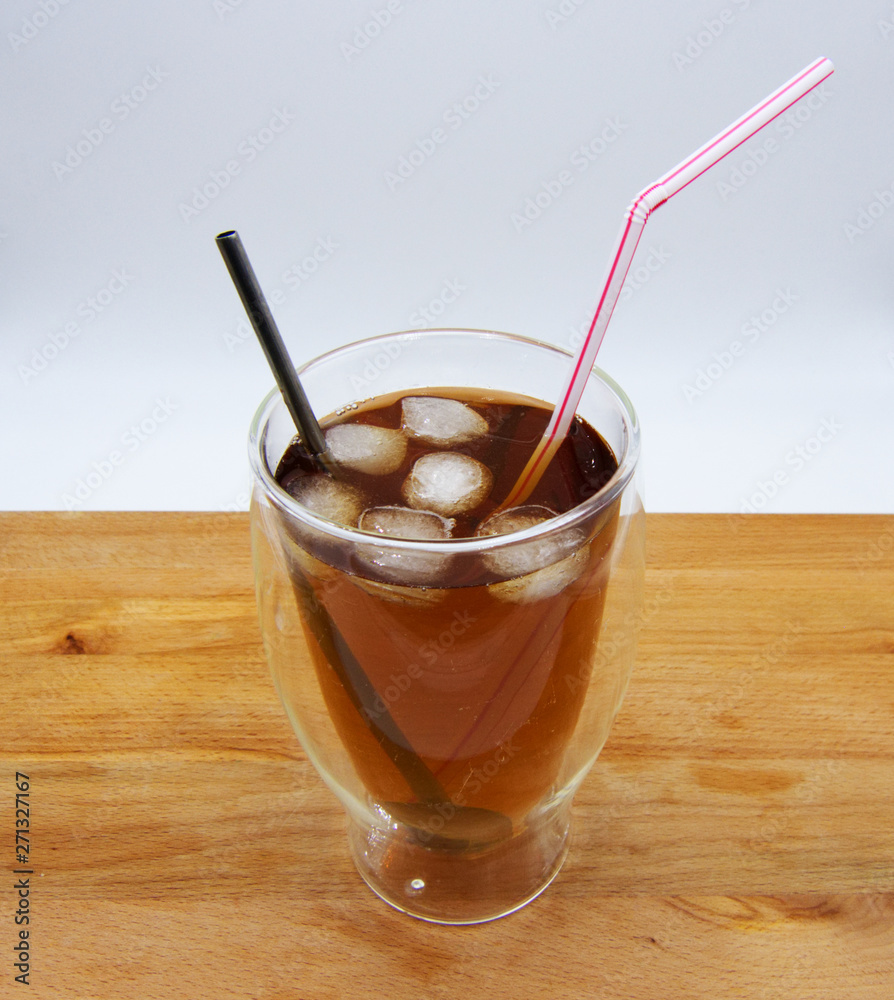 Iced tea with red and blue straw on wooden table, white background Iced tea with red and blue straw on wooden table, white background