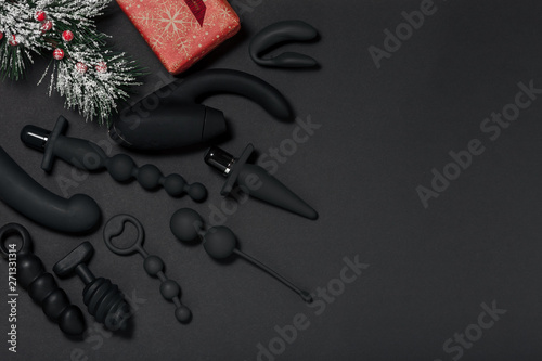 New Year or Christmas festive background for Sex shop. Top view on sex toys for adult. Various sex gadgets  (dildo, butt plug, anal balls, vibrator, oral sex simulator) Christmas gifts and tree.