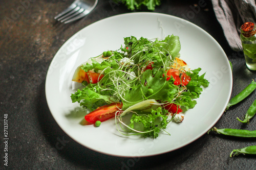 salad vegetable - tomato, lettuce, cheese, microgreen and salad dressing. food background. top