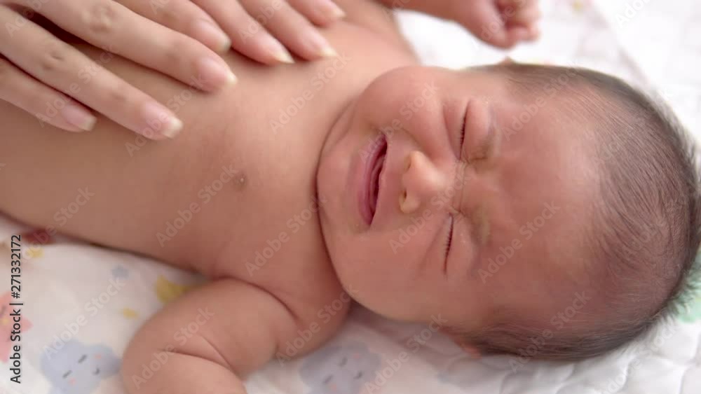 Close up Woman's hands making stomach massage of her newborn baby while baby crying with flatulence. Close up Woman's hands making stomach massage of her newborn baby while baby crying with flatulence.