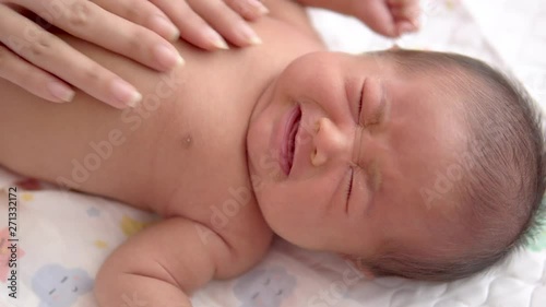 Close up Woman's hands making stomach massage of her newborn baby while baby crying with flatulence.