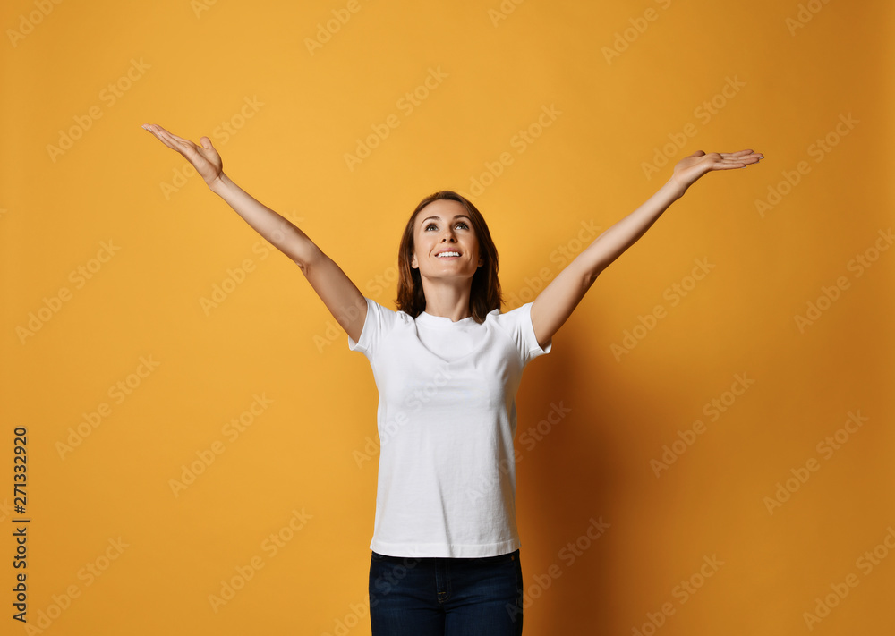 Happy smiling woman holds her spread hands up with open palms and looks up like she is waiting for something fall Happy smiling woman holds her spread hands up with open palms and looks up like she is waiting for something fall