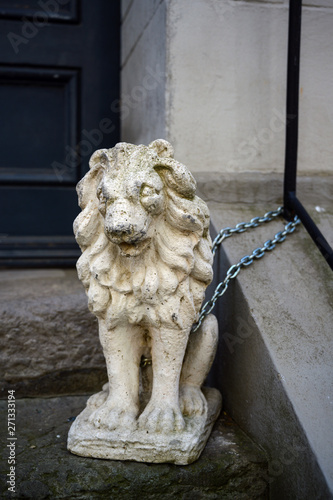 lion sculpture made of stone or gypsum chained in front of a house entrance in the old town of luebeck, germany