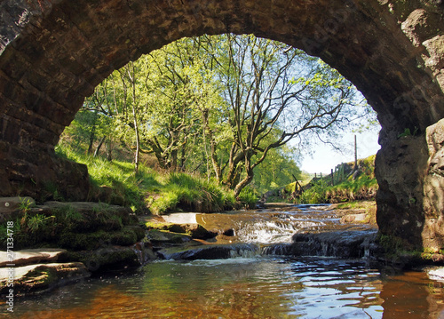 ta view under the old packhorse bridge at lumb hole falls in woodland at crimsworth dean near pecket well in calderdale west yorkshire photo