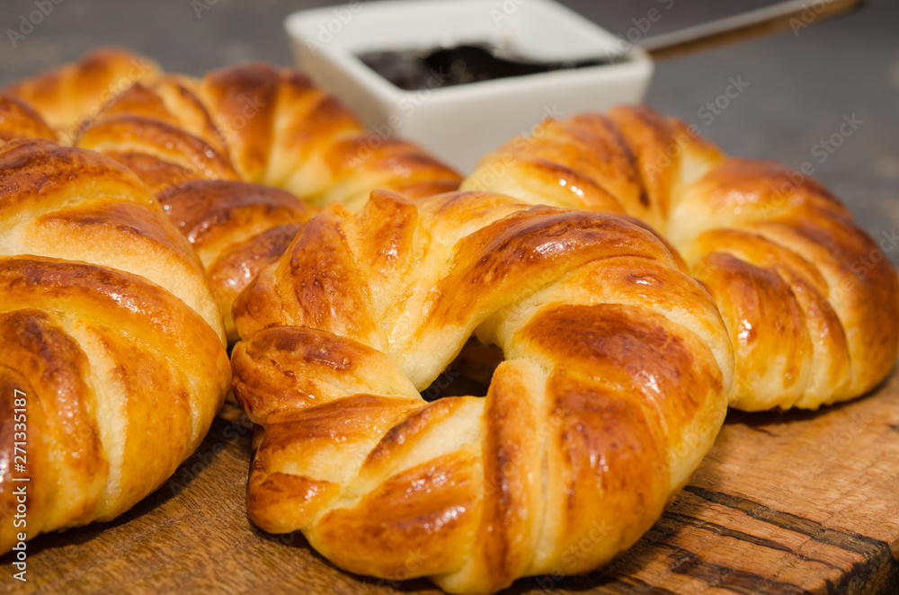 Sweet fresh baked buns served with jam on rustic wooden board 