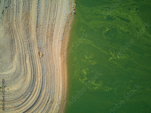 Aerial view of the Valdecañas reservoir, with green water from the algae and natural lines of the descent of the water. Natural texture photo