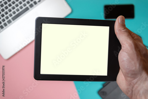 Close up male hands holding a tablet on office table background. Branding stationery mockup scene, blank objects for placing your design.