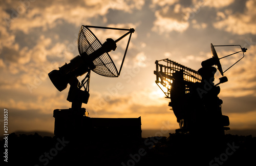 Silhouettes of satellite dishes or radio antennas against sunset sky. Space observatory.