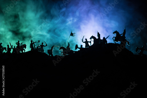 Medieval battle scene with cavalry and infantry. Silhouettes of figures as separate objects, fight between warriors on dark toned foggy background with medieval castle.