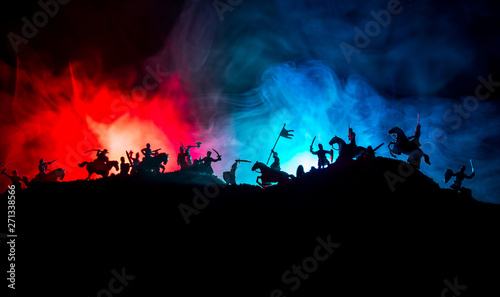 Medieval battle scene with cavalry and infantry. Silhouettes of figures as separate objects, fight between warriors on dark toned foggy background with medieval castle.