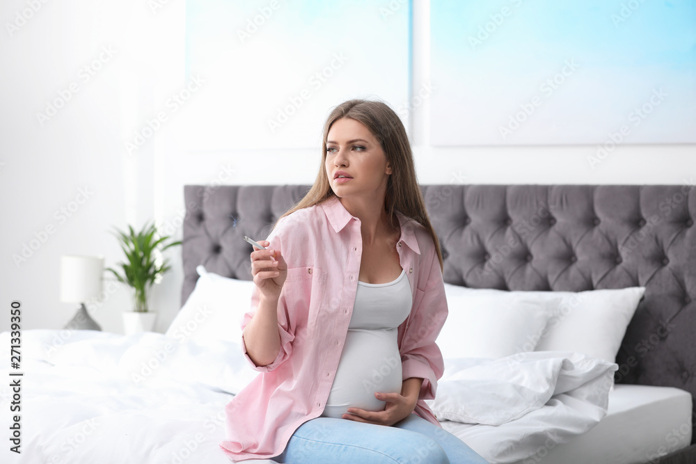 Young pregnant woman smoking cigarette in bedroom. Harm to unborn baby Young pregnant woman smoking cigarette in bedroom. Harm to unborn baby