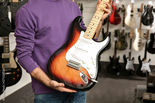 Young man with guitar in music store, closeup