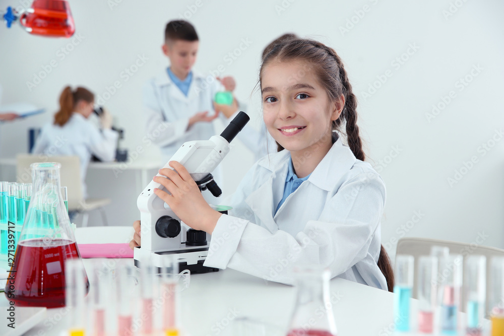 Schoolgirl with microscope at table in chemistry class Schoolgirl with microscope at table in chemistry class