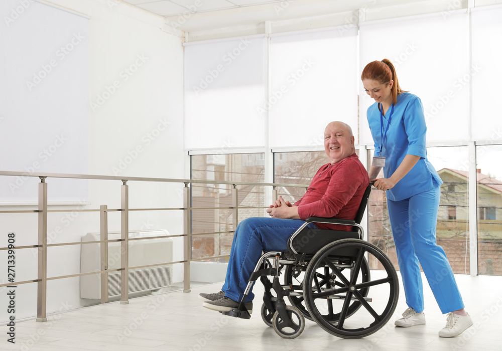 Nurse assisting senior man in wheelchair at hospital