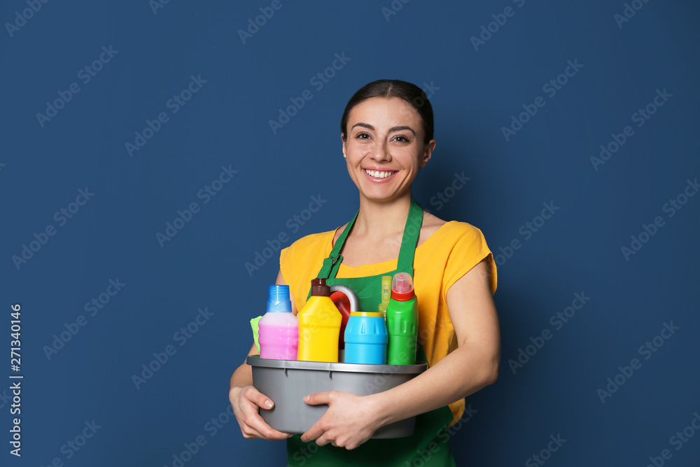 Woman with basin of detergents on color background Woman with basin of detergents on color background