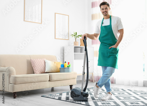 Portrait of janitor with vacuum cleaner in living room