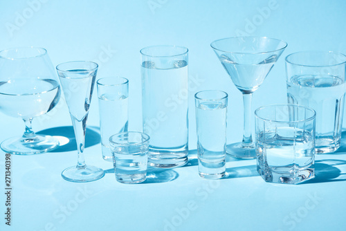 transparent glasses with clear water on blue background