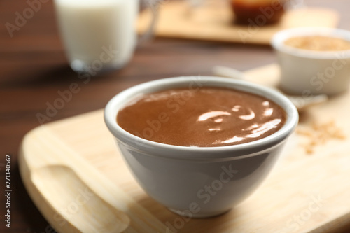 Bowl with caramel sauce on board, closeup
