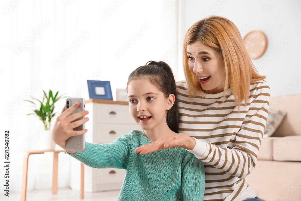 Mother and her daughter using video chat on smartphone at home