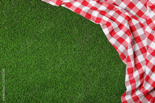 Picnic tablecloth on grass, top view. Space for text photo