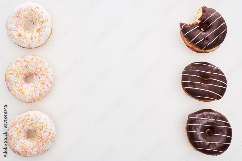 top view of sweet chocolate and white doughnuts with sprinkles on white background with copy space top view of sweet chocolate and white doughnuts with sprinkles on white background with copy space