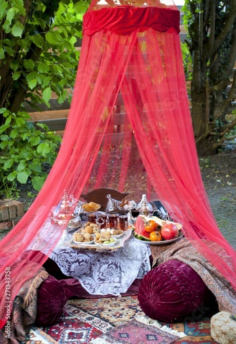 Oriental tea tray and cookies symbolising Moroccan hospitality, Islamic holidays food with decoration. Ramadan kareem. Eid mubarak. Oriental hospitality concept. Tea glasses and pot, traditional delig photo