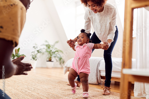Photos Parents At Home Encouraging Baby Daughter To Take First Steps