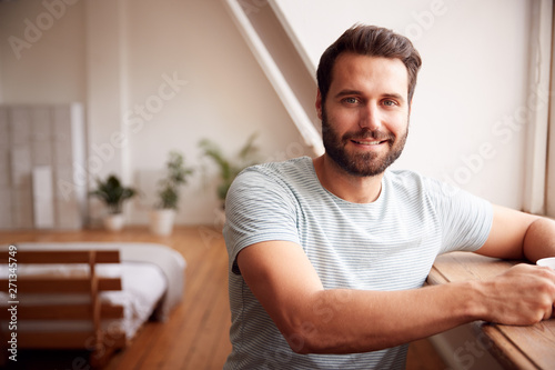 Portrait Of Young Man Relaxing In Loft Apartment With Hot Drink