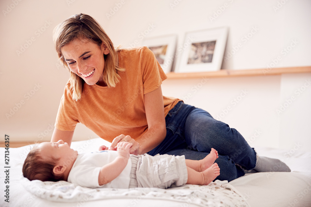Loving Mother With Newborn Baby Lying On Bed At Home In Loft Apartment Loving Mother With Newborn Baby Lying On Bed At Home In Loft Apartment