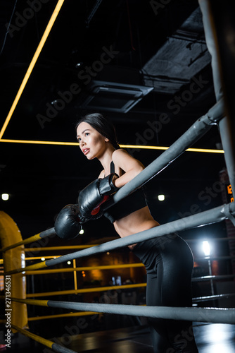 low angle view of athletic woman in boxing gloves standing in sports center